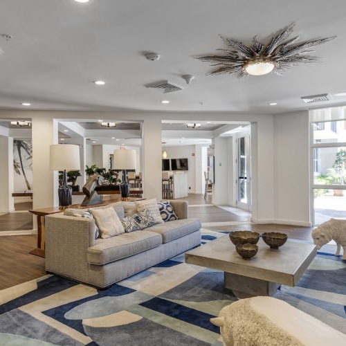 Bright resident lounge at Paraiso Miami with blue and white rug, modern coastal seating, and dining area.